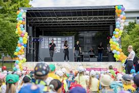 Aufnahme der Bühne während der Vorstellung der Initiatoren des Sommerfests. Im Vordergrund sind dutzende Kinder zu sehen.