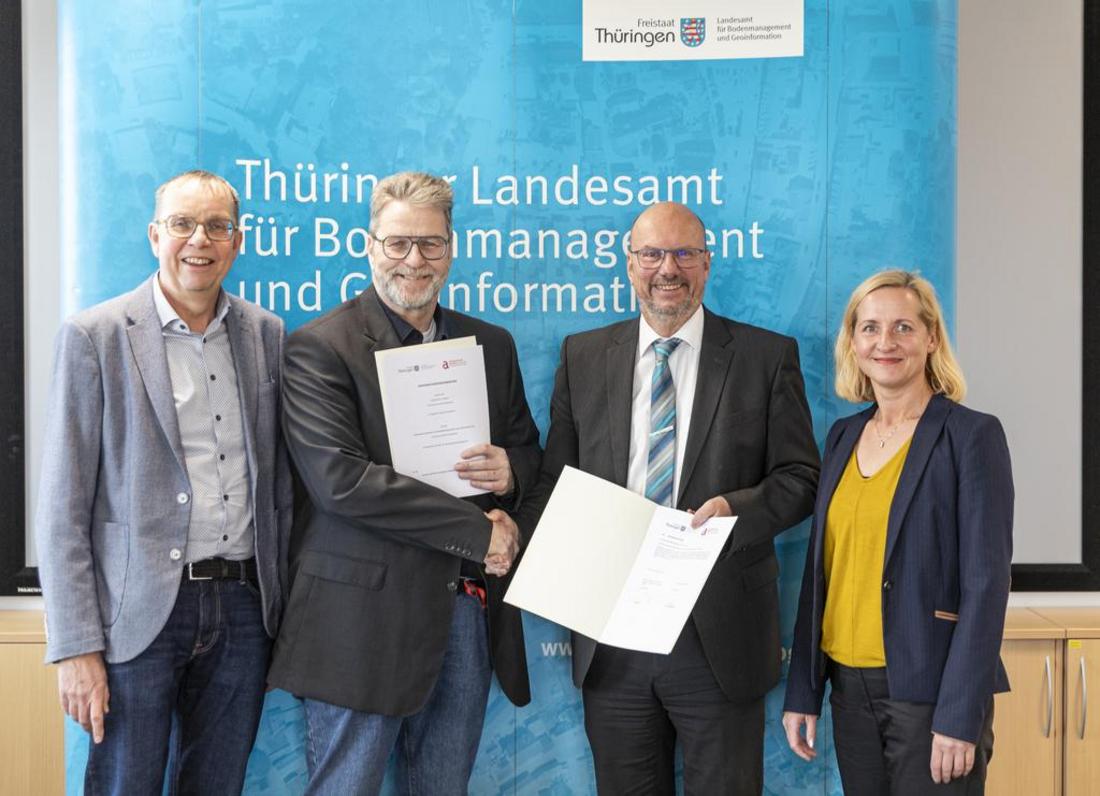 Gruppenbild der Vertragspartner mit der Vereinbarung in den Händen vor einem blauen Banner des TLBG