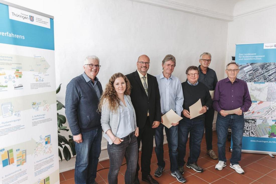 Die Hauptakteure des Flurbereinigungsverfahrens beim Gruppenfoto stehend zwischend zwei RollUps des TLBG