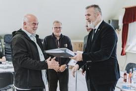 Steffen Schütz (TMDI) übergibt Bürgermeister Jan Heineck Exemplar des Flurbereinigungsplanes. TG-Vorsitzender Wilfried Höfer und Uwe Köhler (TLBG) schauen im Hintergrund zu.