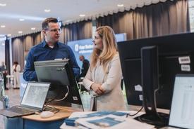 Ein Kollege des TLBG im Fachgespräch mit der Staatssekretärin. Beide stehen an einem mobilen Tresen mit Computerarbeitsplatz am Stand des TLBG.