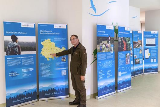 Uwe Greiner (UNESCO-Biosphärenreservat Thüringer Wald) zeigt auf ein Roll-up der Wanderausstellung