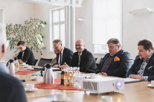 Schulterblickperspektive hin Uwe Köhler und VIPs, die am Tisch platzgenonmmen haben