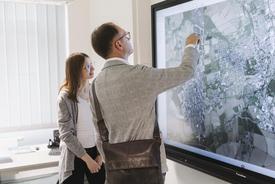 Staatssekretär Knoblich am riesigen wandmontierten Touchscreen. Gezeigt wird das Projekt einer TLBG-Studentin.