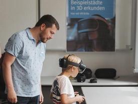 Kleiner Junge mit Holo-Lens auf dem Kopf und Controller in der Hand beim Erkunden einiger Thüringer Städte mit 3D-Gelände- und Häusermodellen