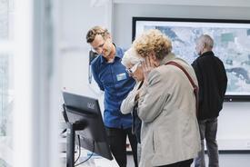 Zwei ältere Besucherinnen begutachten mit 3D-Brillen eine 3D-Kartenillusion auf einem Printprodukt.